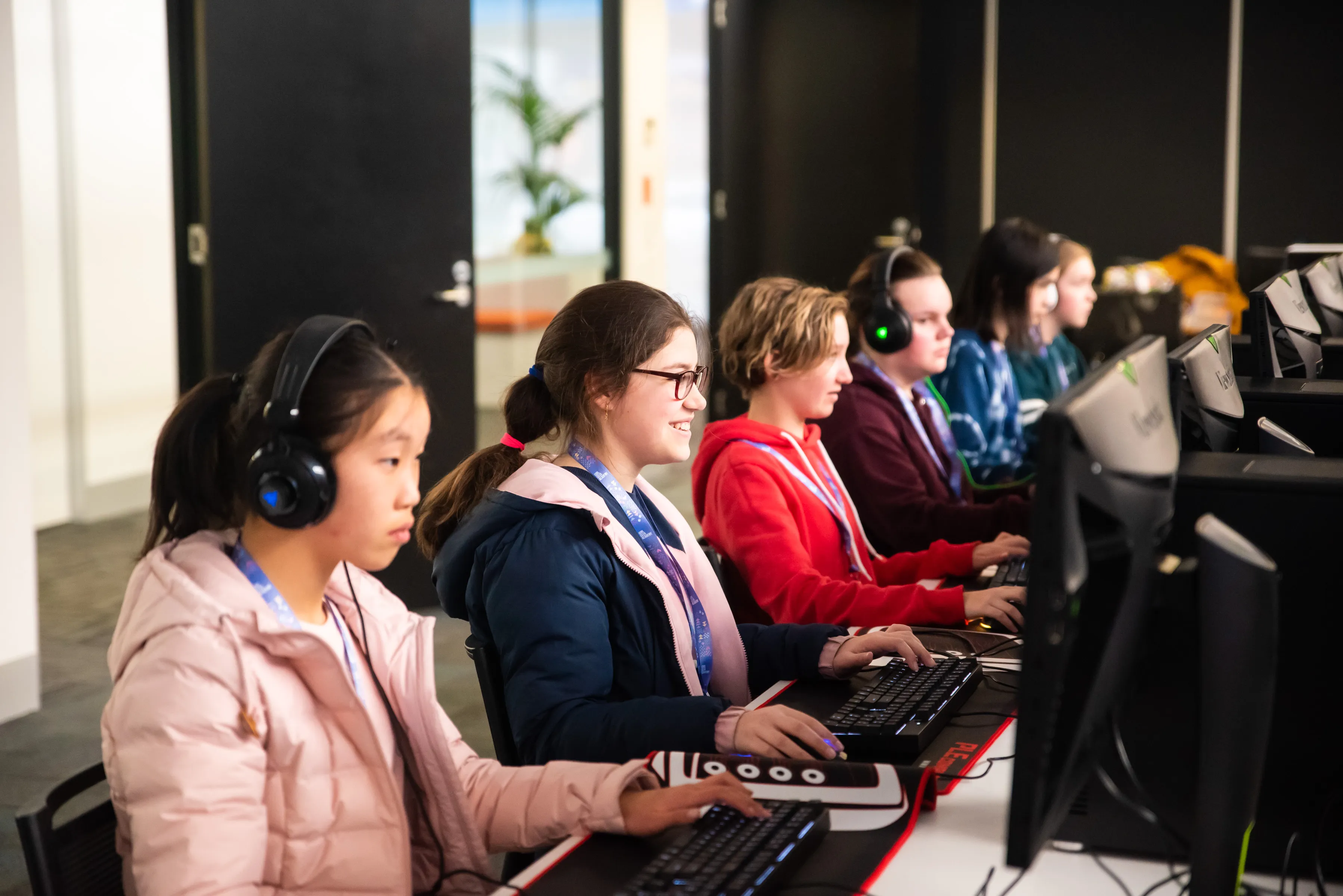 Girls in headphones at a row of computers
