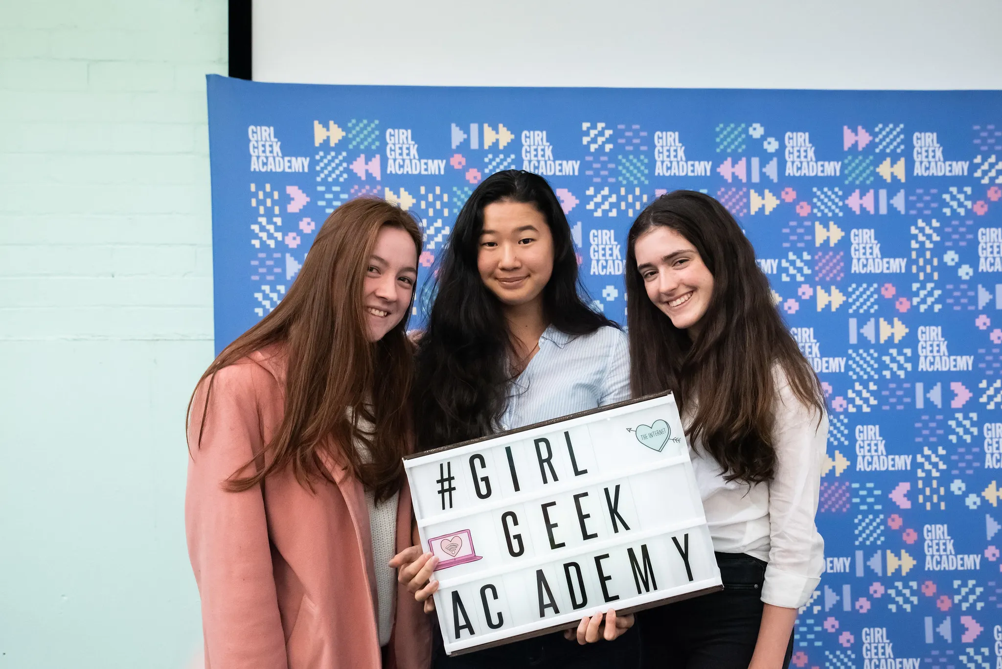 Three girls holding a #GirlGeekAcademy sign
