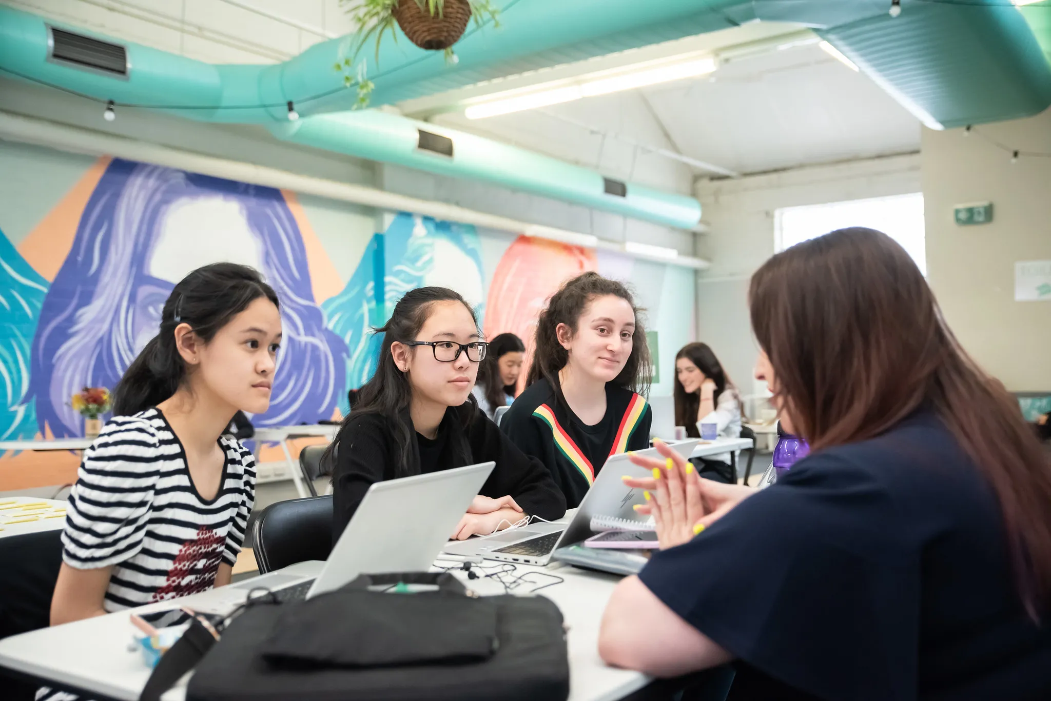 Participants working at laptops in front of a mural