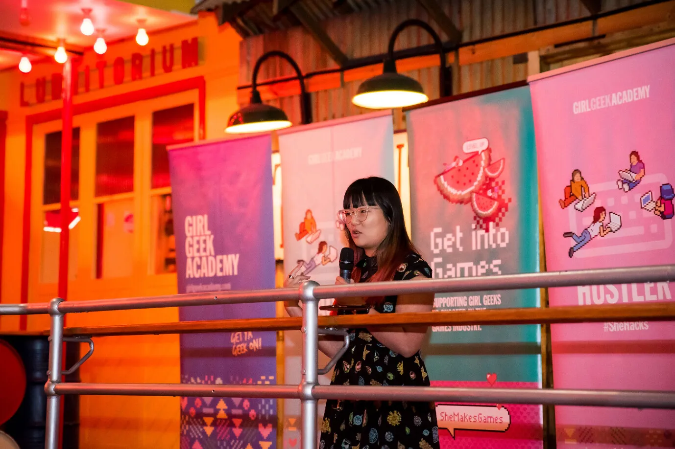 A speaker addressing the cohort in front of Girl Geek Academy banners