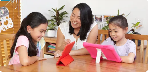 A mum and two daughters learning on tablets at home