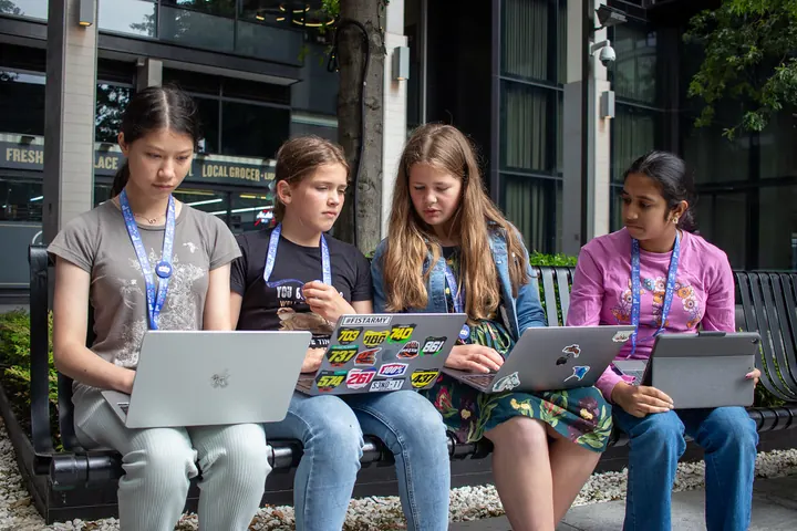 Four students on a bench, each with her own laptop