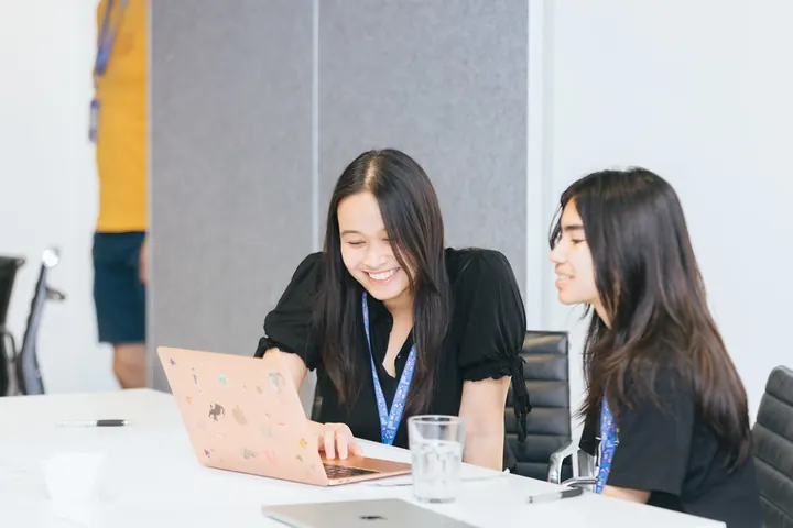 Two students laughing over a laptop
